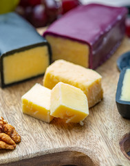 Mini black and dark red waxed cheddar cheeses made from West Country milk and and age-old methods in England