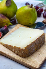 Piece of French cheese Tomme de Brebis made from sheep milk served as dessert with fresh figs and pears