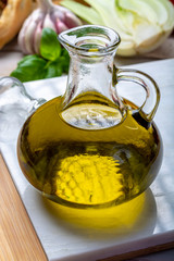 Virgin natural olive oil is glass bottle, served with traditional Mediterranean food