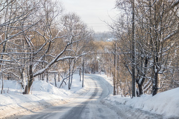 The road in the winter forest. Snow picture. Branches of trees in the snow hang over the road.