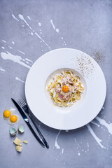 Pasta carbonara with quail egg, plate full of Italian tagliatelle with ham and cheese.