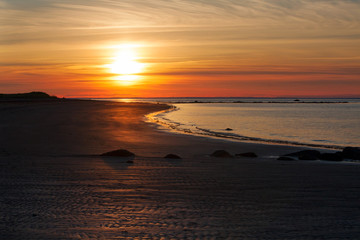Naklejka premium Reddish brown foggy sunset by the shore