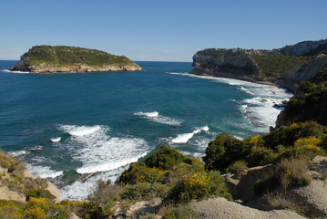 Fototapeta na wymiar Coastal view with waves breaking on the shoreline in spring, to the island of Portichol from the headland at Cap Prim, Javea, Alicante Province, Spain