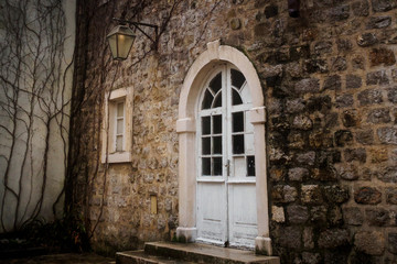 White semicircular door with glass in the stone wall of the old town in Budva, Montenegro