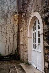 Fototapeta na wymiar White semicircular door with glass in the stone wall of the old town in Budva, Montenegro