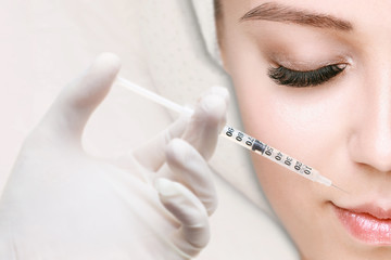 Woman receiving injections in the lips zone lying on the medical couch. Close up of hands of cosmetologist making injection in female lip. Plastic surgery concept.
