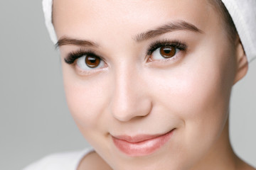 Obraz premium Eyelash extension procedure. Beautiful woman with long eyelashes, trendy eyebrows and perfect glow clean skin. Girl in beauty salon getting facial treatment. 