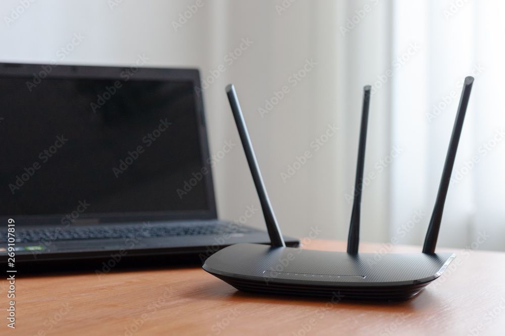 Poster wireless wifi router and laptop at wooden table indoors. window behind. wireless connection concept.