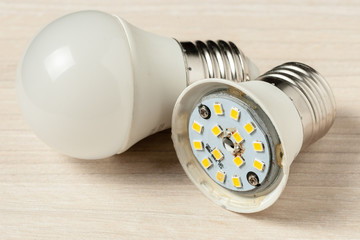 repair broken led light bulb. burned lamp at light wooden background. opened lamp.