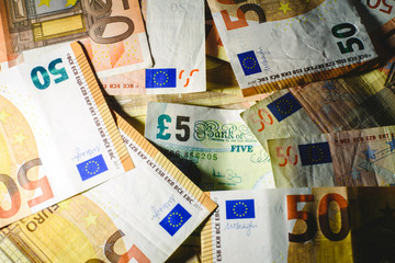 Stack of euro bills cornering a pound note by the brexit.