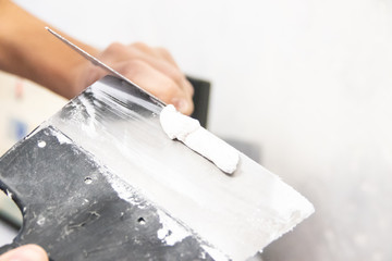 Male hand with a spatula putty wall. . Align the wall. White wall. Putty on the wall
