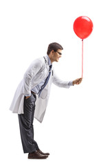 Male doctor giving a red balloon