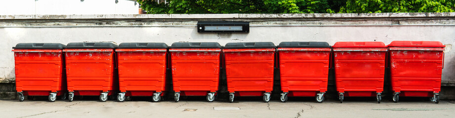 Row of red garbage bins in the city.