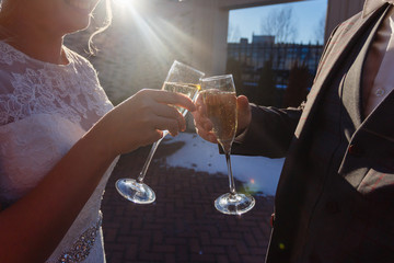 Dating or wedding concept - couple drinking white wine or champagne outdoors. A young couple clink glasses with an alcoholic drink. Sun glare in the glasses.