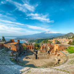 Ruins of ancient Greek theater in Taormina and Etna volcano in the background.