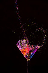 Closeup of Droplets Along With Burst of Colorful Liquid in Wine Glass. Isolated Over Black.