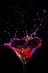 Explosion of Colorful Liquid in Wine Glass with Strawberry. Isolated Over Black Background