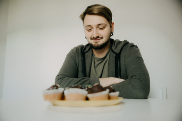 Fototapeta na wymiar A young hipster on a diet with cupcakes