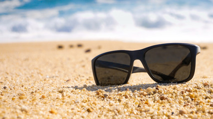 Fototapeta na wymiar Sunglasses on sandy beach in summer. Space on left for text.