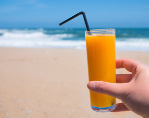 Delicious glass of fresh orange juice at the beach in summer