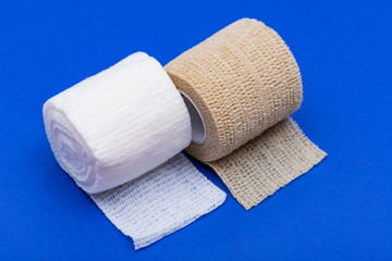 Hospital Grade Sterile Rolled Gauze and Elastic Self-Adhering Compression Bandage (Cohesive Bandage) on blue background.