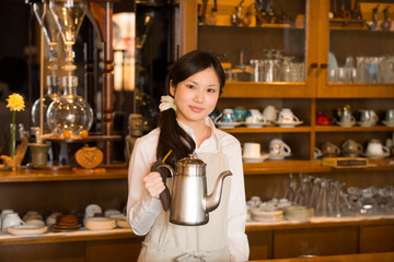 ポットを持ち微笑むカフェの店員