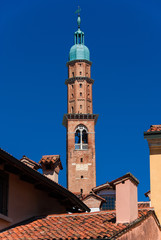 Obraz premium Bissara Tower rises above historic center tradtional red tile roofs and old chimney. Completed in the 15th century, it's the tallest building in Vicenza