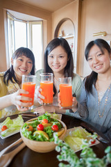 野菜ジュースを持ち微笑む3人の女性