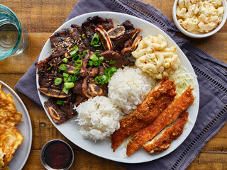 hawaiian bbq plate with mix of chicken katsu, korean kalbi beef short ribs, rice, and macaroni salad overhead composition