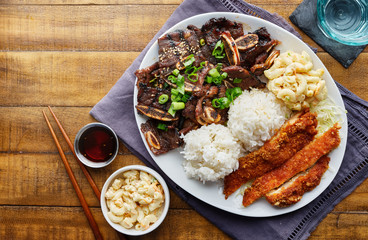 hawaiian bbq plate with mix of chicken katsu, korean kalbi beef short ribs, rice, and macaroni salad overhead composition