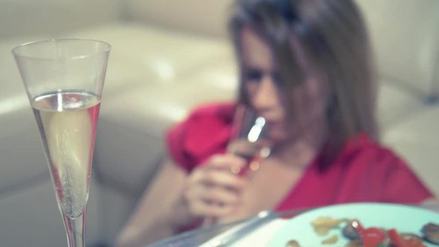 woman gets drunk at home alone at a table set for two for a romantic date, as her partner did not come on a date