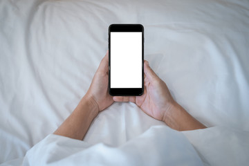 Woman holding on her smartphone while sleeping in bed background.