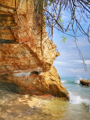 Beautiful single rock formation on the seashore with splashing swash  silky smooth water reflection background.
