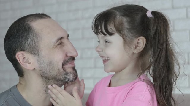 Kid playing with dad. Cute little girl girl hugs dad.