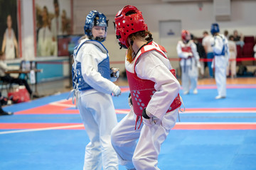 Obraz premium two girls in blue and red Taekwondo equipment are fighting at doyang