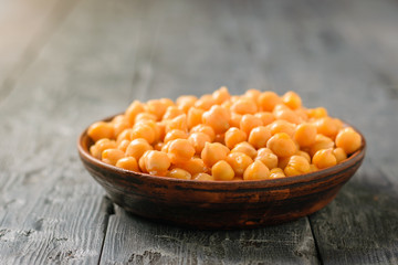 Boiled chickpeas in a clay bowl on a black wooden table. Minimalism.