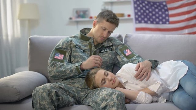 US soldier stroking head of sleeping on his knees girlfriend, care and love