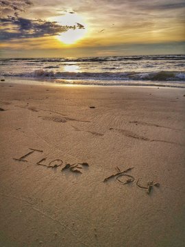 A love message I love you written on the sandy beach.