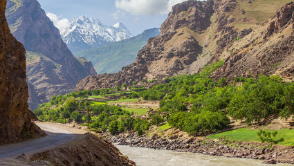 Road in a deep mountain gorge. Below is a tumultuous river Panj. Pamir Highway, Tajikistan. On the...