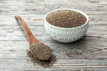 Bowl and spoon with chia seeds on wooden table
