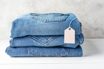 Stack of jeans clothes with tag on table