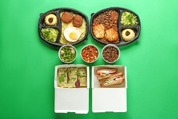 Containers with delicious food on color background