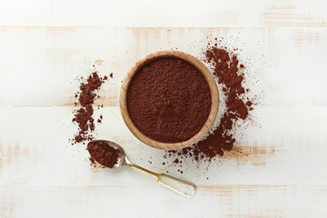 Bowl with cocoa powder on white wooden background
