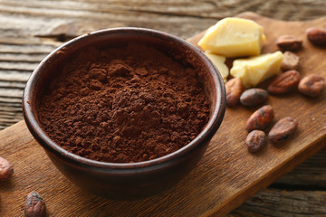 Bowl with cocoa powder on wooden background