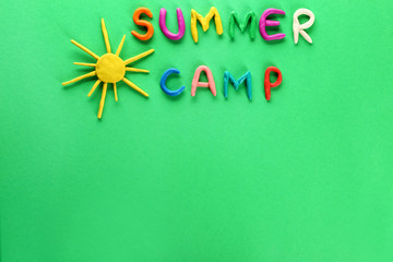 Text SUMMER CAMP and sun made of plasticine on color background
