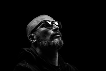 Bald man with grey beard in sunglass on dark background