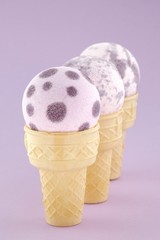 bath bomb set. Purple  organic bath bombs with flower extract in waffle cones on a softly purple background.Cosmetic ice cream for the body.Organic Bio Body Cosmetics.