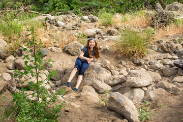 Naklejka na ściany i meble Little girl carefully climbing down rocks in the woods at a park
