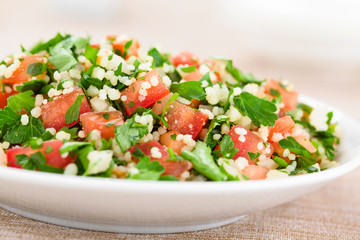 Fresh vegan Tabbouleh salad made of tomato, parsley, onion and couscous on plate (Selective Focus, Focus in the middle of the image)