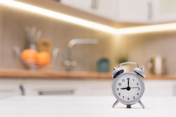 Selected focus on gray alarm clock on a kithen white wooden table